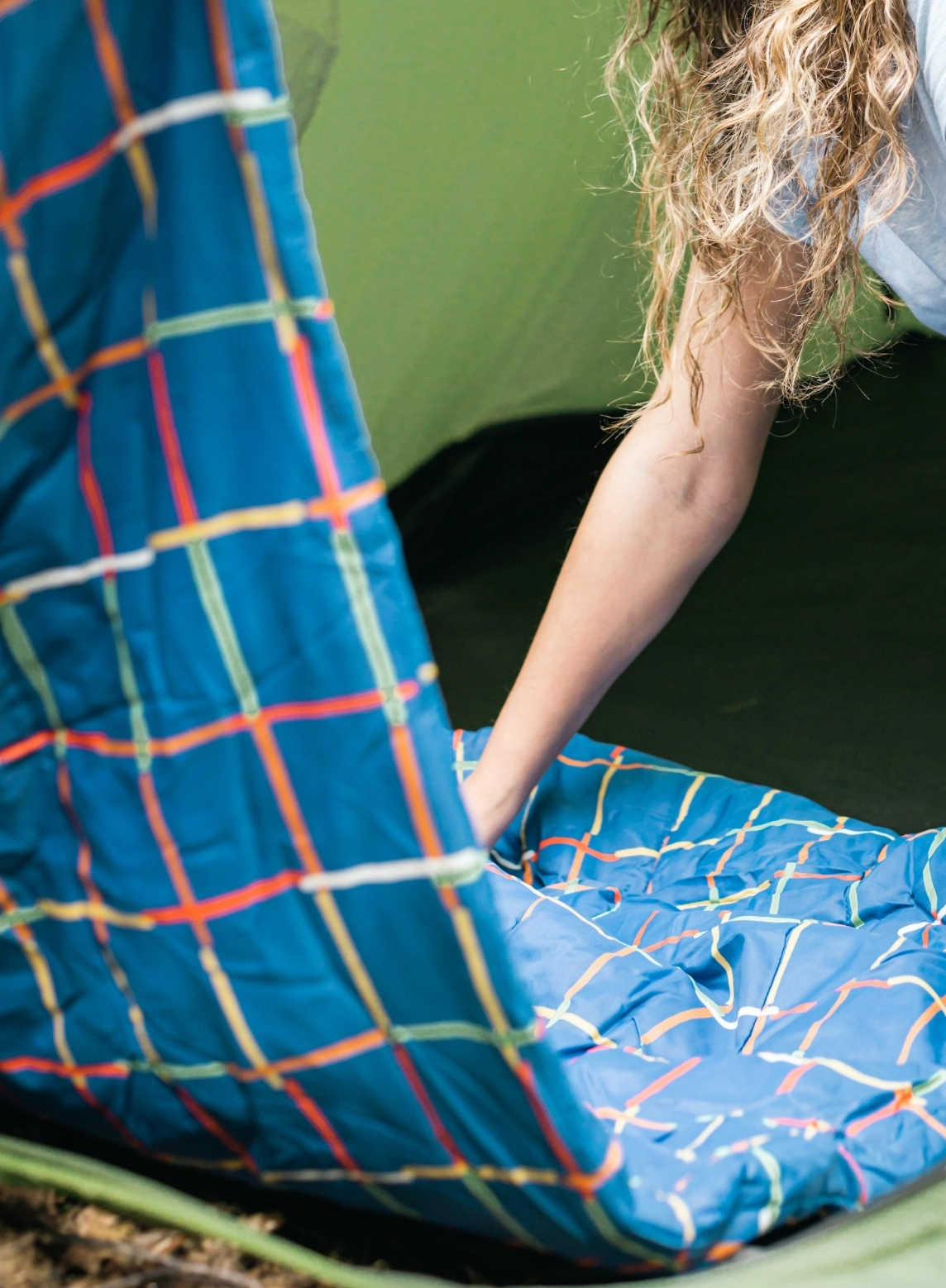 A photograph of a person arranging a sleeping bag.