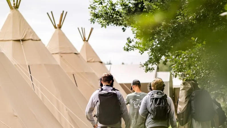A photograph of people walking beside tipis at Lost Village.