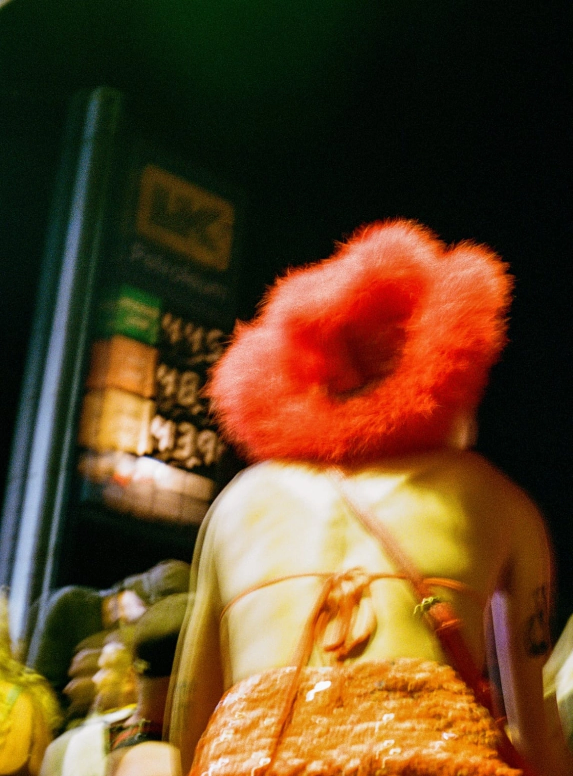 A blurred photograph of a person in a red fluffy hat at the gas station set at Lost Village.