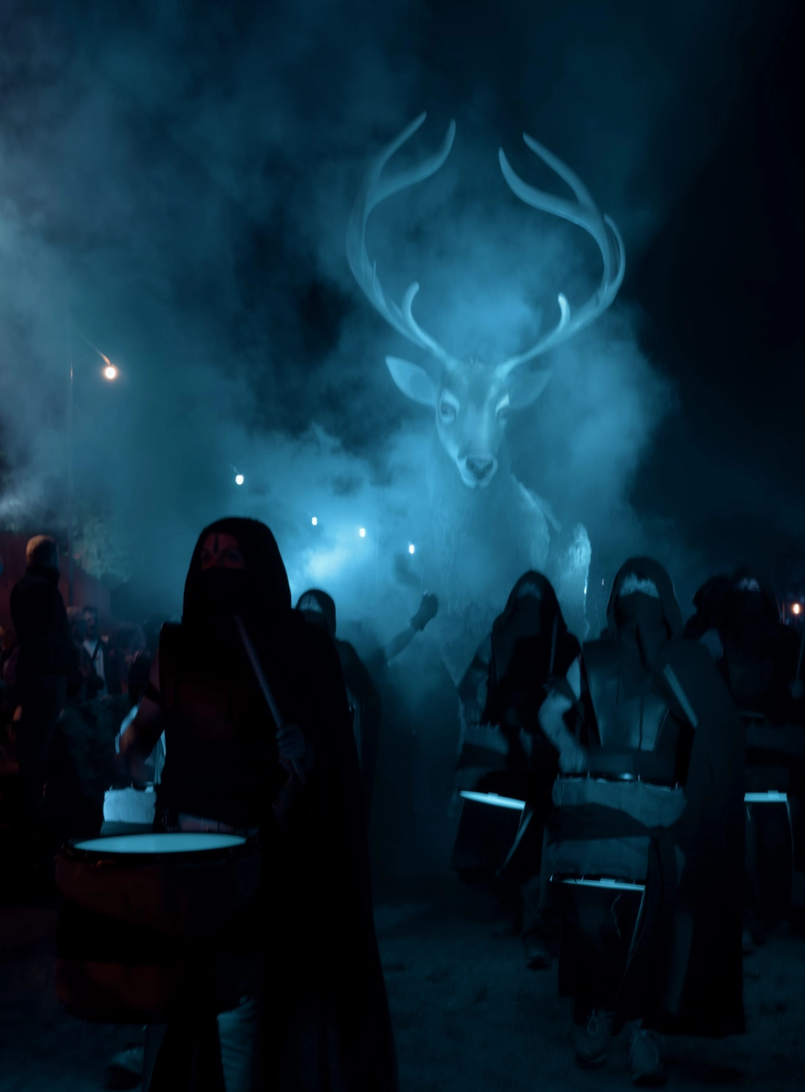A photograph of a parade of hooded people leading a large wooden stag at Lost Village.