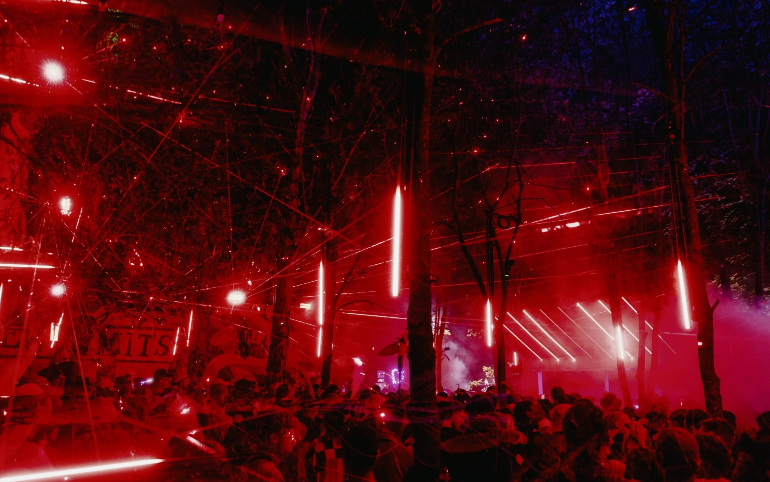 A photograph of festival goers at a stage at Lost Village festival, with red LED and laser lighting and fog.
