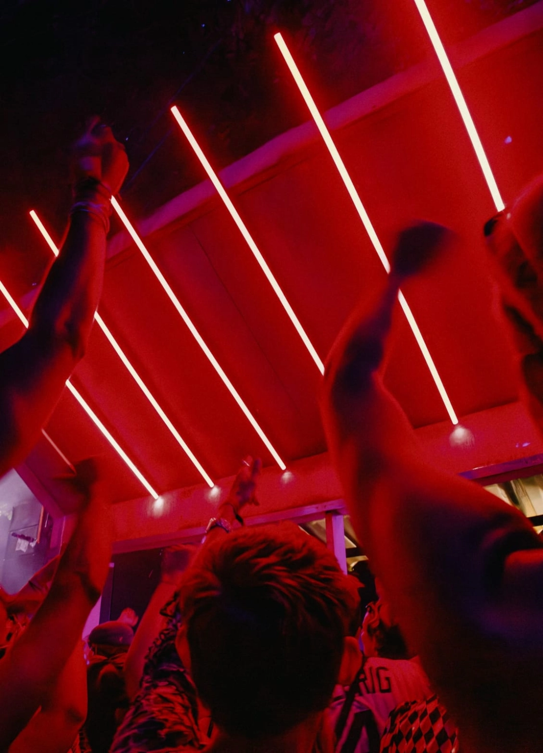A photograph of people dancing at a stage at Lost Village, with a backdrop of red LED lights.