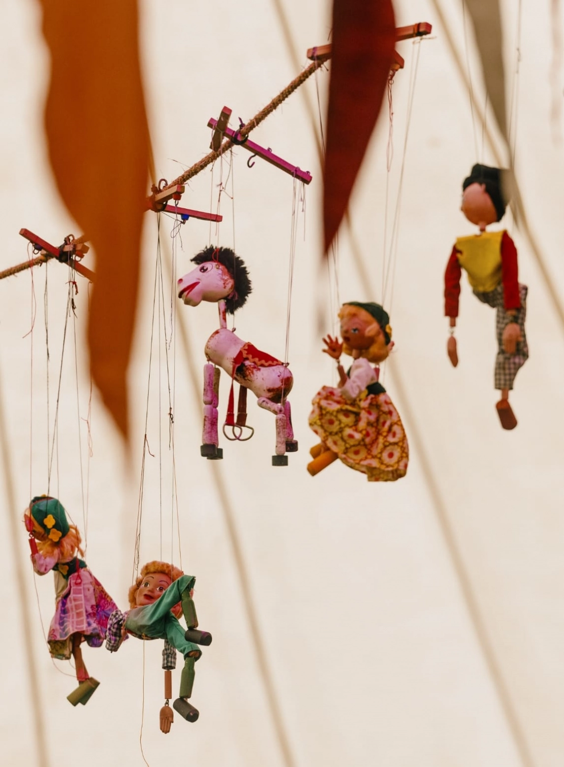 A photograph of marionettes suspended from the top of a tent at Lost Village, at the Institute of Curious Minds where talks are held.