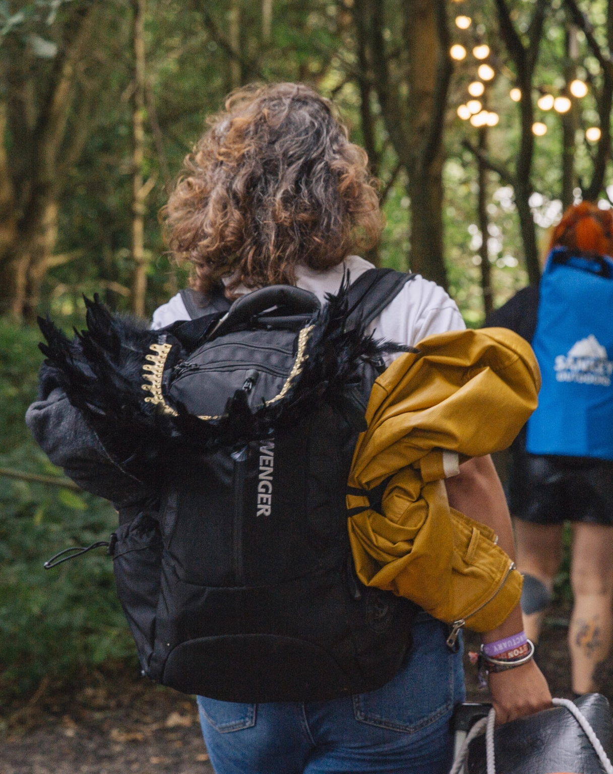 A photograph of the back of a person carrying a backpack and camping equipment.