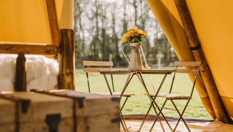 A photograph of the interior of the ultimate tipi, a premium accommodation option at Lost Village. Featuring two chairs and a table.